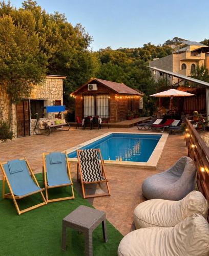 a backyard with a pool and chairs and a table at Rickystone in Jiwār al Bawāshiq
