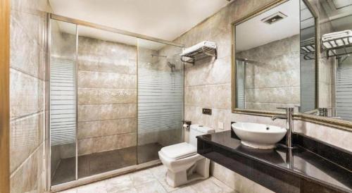 a bathroom with a sink and a toilet and a mirror at Cheerful Hotel in Nanhai