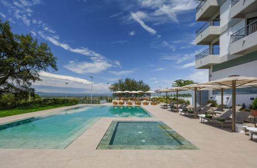 a pool at a hotel with chairs and umbrellas at Meliá Castelo Branco in Castelo Branco