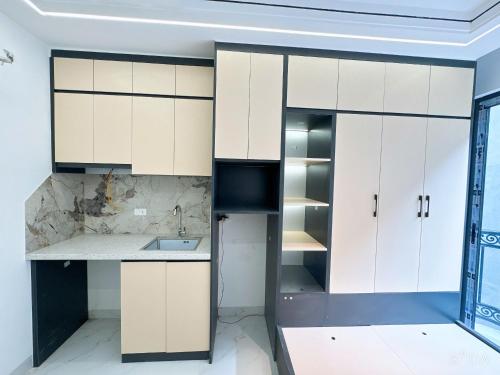 an empty kitchen with white cabinets and a sink at Sunshine Housse with Balcony in Centre in Ho Chi Minh City