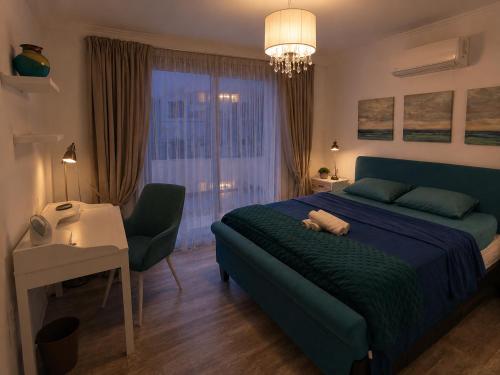 a bedroom with a blue bed and a desk and a chair at Aquamarine in Oroklini
