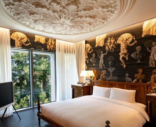a bedroom with a large bed with a painting on the ceiling at The Siena Resort in Seogwipo