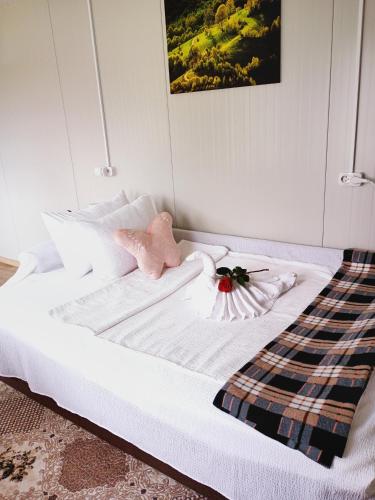 a white bed with a pink stuffed animal on it at Căsuțele De Sub Codru in Colacu