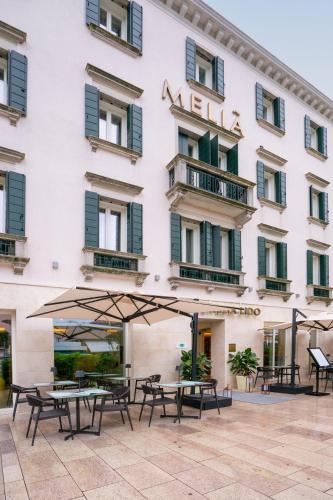 a hotel with tables and umbrellas in front of it at Meliá Venezia Lido in Venice-Lido