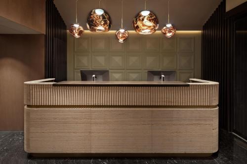 a lobby with a counter with two sinks and lights at MiM Andorra member of Meliá Collection in Escaldes-Engordany