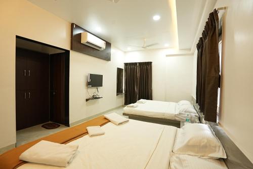 a living room with two beds and a tv at Hotel Shreyash in Solapur