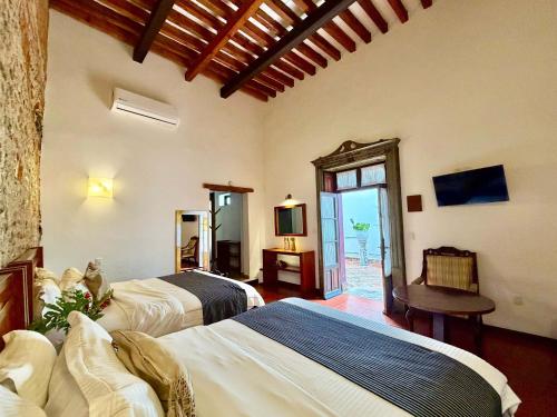 a bedroom with two beds and a table and a television at El Serafin Hotel Boutique in Querétaro