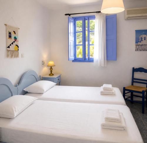 two beds in a room with a window at Porto Sikinos Hotel in Alopronia