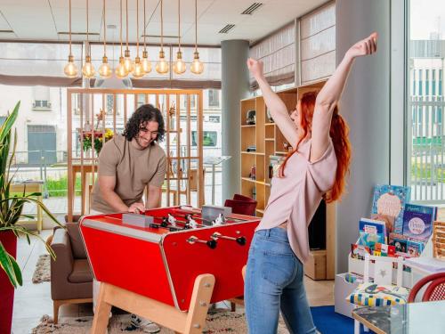 a man and a woman playing with a ping pong table at Aparthotel Adagio Access Nancy Centre in Nancy