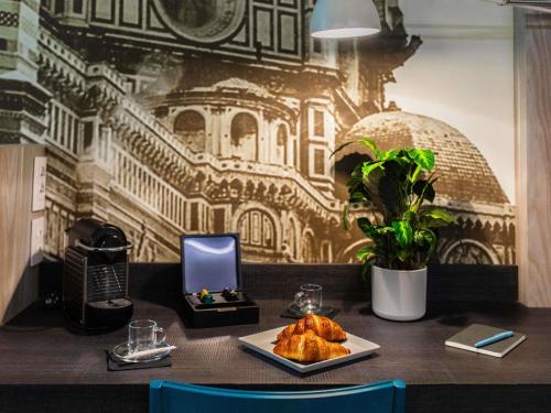 a table with a phone and a plate of food at Mercure Firenze Centro in Florence