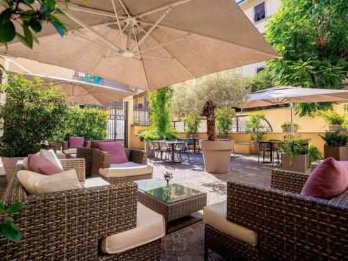 an outdoor patio with chairs and tables and an umbrella at Mercure Firenze Centro in Florence