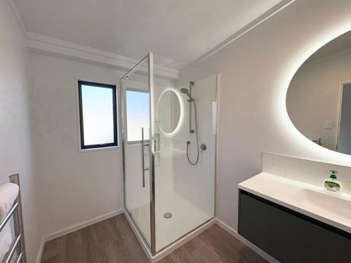 a bathroom with a shower and a sink and a mirror at The Bach in Lake Tekapo