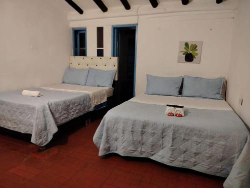 two beds in a room with shoes on them at Hotel Alma Divina in Villa de Leyva