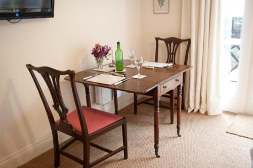 a dining room table with two chairs and a bottle of wine at Fox Inn in Darsham