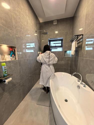 a woman standing in a bathroom next to a tub at OLA LUXURY HOTEL Parakou in Parakou