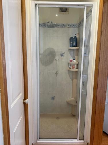 a shower with a glass door in a bathroom at Bethel Homestay in Watsonia North