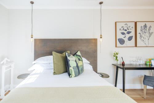 a bedroom with a white bed with a wooden headboard at Whispering Oaks Guest House in George