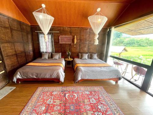 two beds in a room with a rug on the floor at Stilla Home in Tả Van