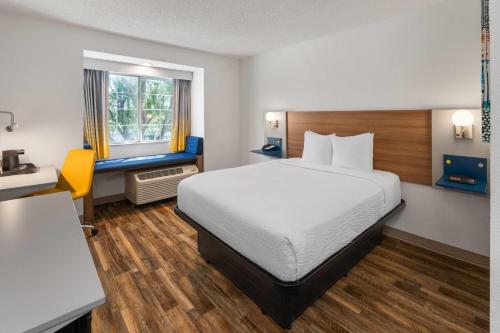 a hotel room with a bed and a desk and a window at Microtel Inn & Suites by Wyndham Denver Airport in Montbello