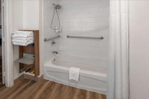 a bathroom with a bath tub with a shower curtain at Microtel Inn & Suites by Wyndham Denver Airport in Montbello