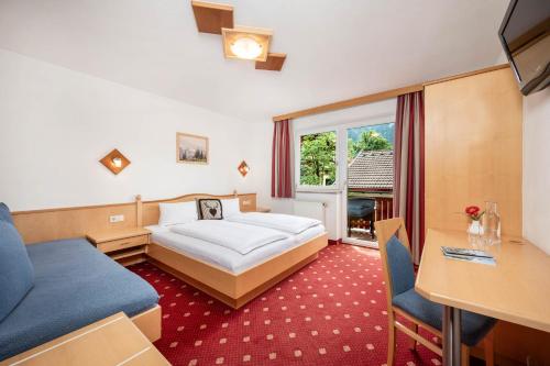 a hotel room with a bed and a desk at Pension Posauner in Dorfgastein