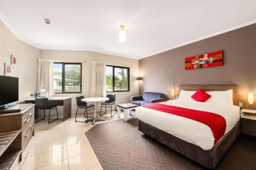a hotel room with a bed and a desk and chairs at Quality Hotel City Centre in Coffs Harbour