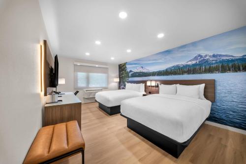 a hotel room with two beds and a painting of a lake at Clarion Pointe Kent - Seattle South in Kent