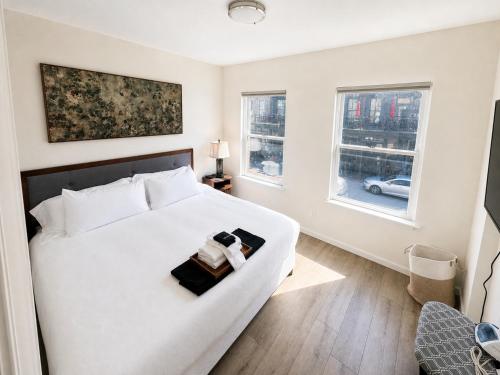 a bedroom with a white bed and two windows at Stylish 2BR Retreat - Concrete & Canopy in St. Charles