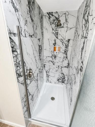 a bathroom with a shower with a white marble wall at The Rustic Revival - Charming 2BR Retreat in St. Charles