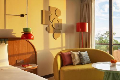 a bedroom with a yellow chair and a table at Kleo Seminyak, part of JdV by Hyatt in Seminyak
