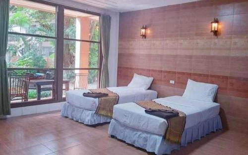 two beds in a room with a large window at Saikaew Villa in Ko Samed
