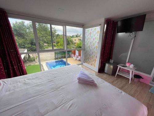 a bedroom with a white bed and a large window at Baan Gon Chompu in Suan Phung