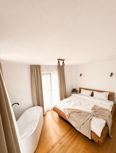 a white bedroom with a bed and a chair at Dor de Munte in Vărtăneşti
