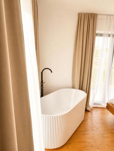 a white bath tub in a room with a window at Dor de Munte in Vărtăneşti