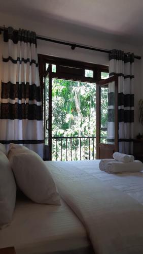 a bedroom with a large white bed with a window at Kadura Resort in Ella