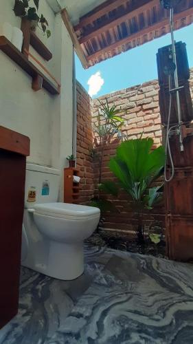 a bathroom with a toilet and a brick wall at Kadura Resort in Ella