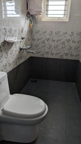 a bathroom with a white toilet and a window at Janani service apartment in Kushālnagar