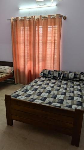 a bed in a room with an orange curtain at Janani service apartment in Kushālnagar