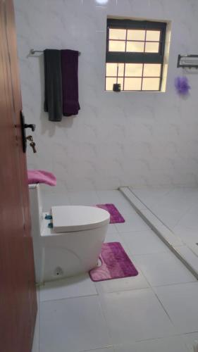 a bathroom with a toilet and purple rugs on the floor at Hidden Gem KAG Kitengela in Stony Athi