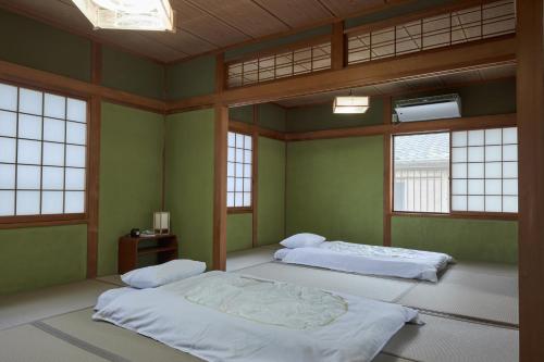 two beds in a room with green walls and windows at Wan Kumano by WhyKumano in Nachikatsuura