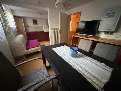 a living room with a table and a tv at Souterrain Zimmer mit Sauna in Klosterlechfeld