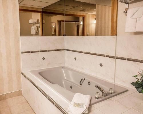a white bath tub in a bathroom with a mirror at Quality Inn & Conference Centre Red Deer - 50th Avenue in Red Deer