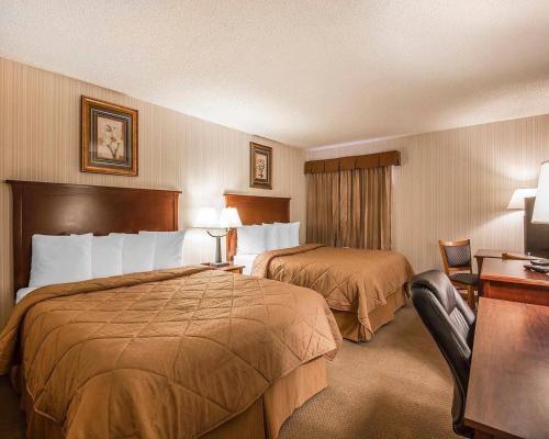 a hotel room with two beds and a desk at Quality Inn & Conference Centre Red Deer - 50th Avenue in Red Deer
