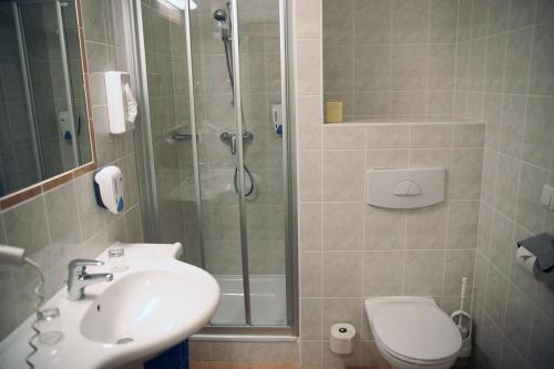 uma casa de banho com um chuveiro, um lavatório e um WC. em Hotel GIP em Grosspetersdorf