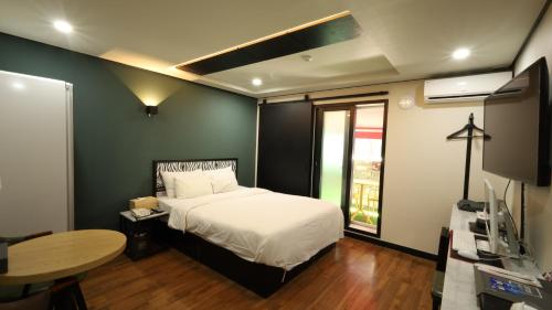 a bedroom with a bed and a table and a window at 수원행궁 넘버25 in Suwon