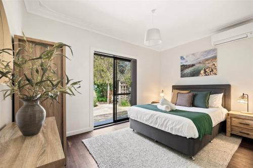 a bedroom with a bed and a large window at Elva Garden Cottage - Dog Friendly - Town Central in Margaret River Town