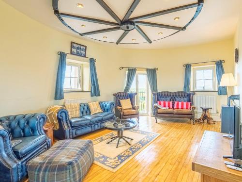 a living room with blue leather furniture and a chandelier at The Windmill in Castletown