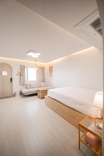 a bedroom with a large bed and a couch at 레이니데이 in Namŭm-ni