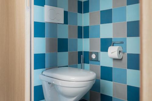 a blue tiled bathroom with a toilet and a roll of toilet paper at Placid Hotel Design & Lifestyle Zurich in Zürich