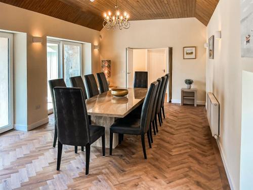 a dining room with a wooden table and black chairs at The Coach House in Auchtermuchty